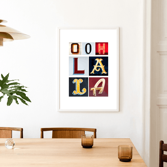 Framed artwork with colourful letters spelling 'Ooh La La' above a dining table. Ooh La La Paris typography fine art print with photographed letters.