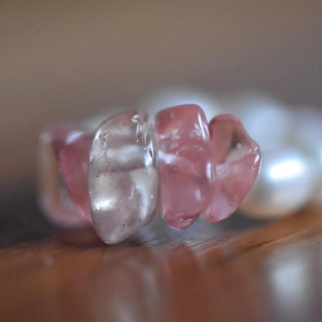 Close-up of a ring with pink and clear gemstones on a wooden surface. Minimal handmade gemstone ring with natural freshwater pearls