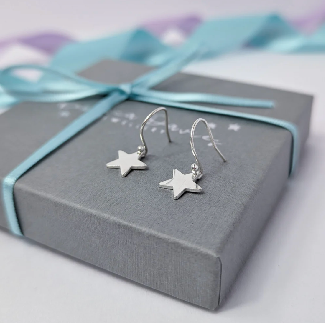 Unique hand-crafted sterling silver star earrings, subtle dangly design, suitable for casual and special occasions.