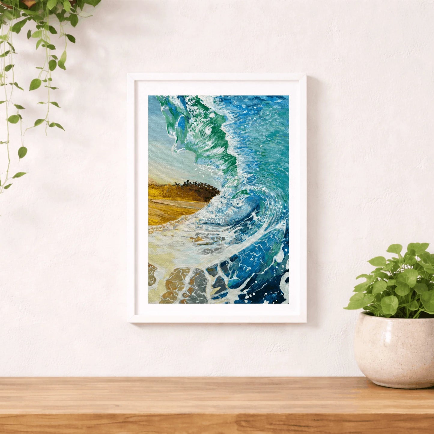 Framed artwork of a beach scene with waves on a wall above a wooden shelf. Coastal wall art print with wave texture and calming tones, made in Wales. 